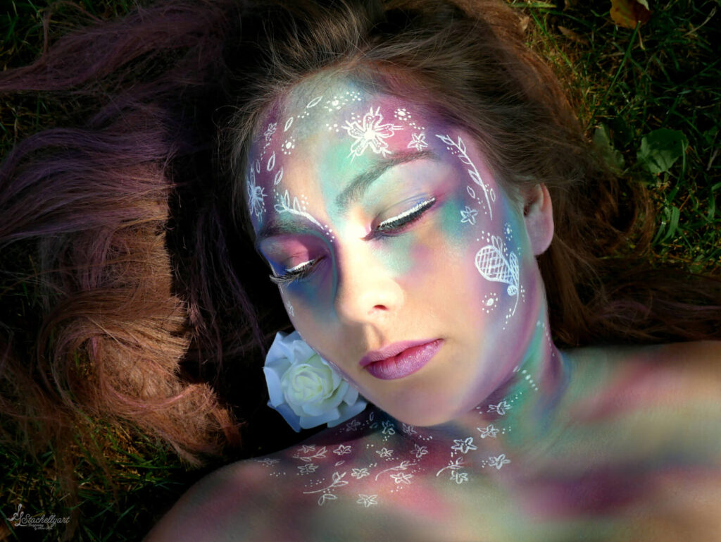 Bodypainting Stachellyart - Mädchen mit Facepainting auf dem Boden liegend mit geschlossenen Augen.