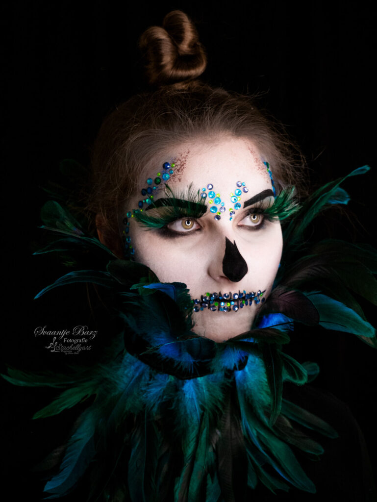 Mädchen mit gemalten Totenkopf mit blauen Perlen und Federkranz u den Hals.