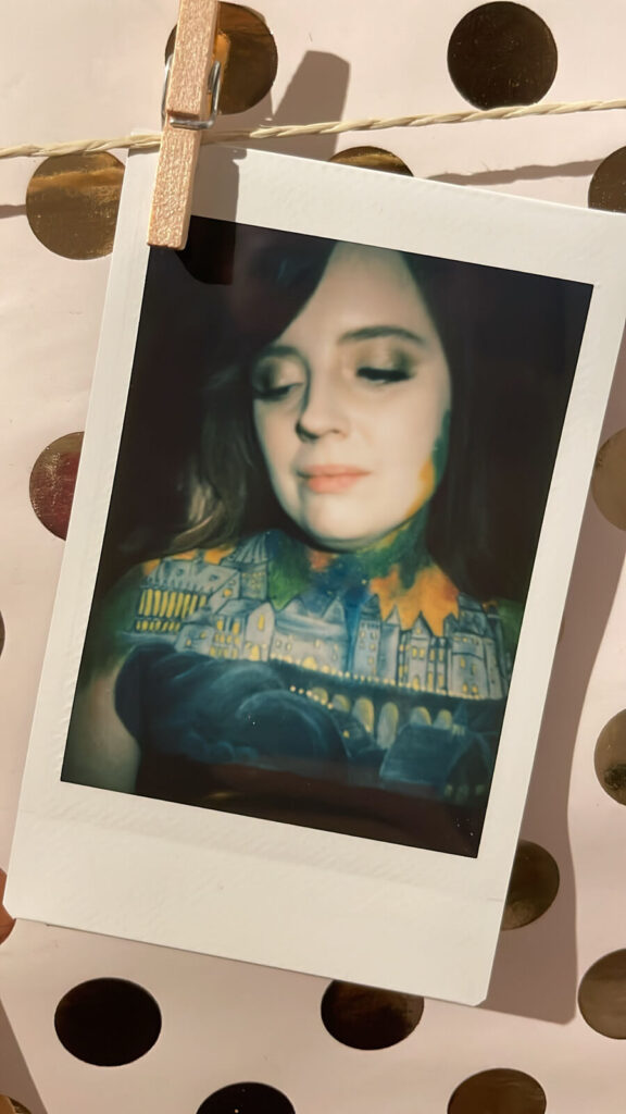 Polaroidbild von Bodypainting Stachellyart - Hogwarts Schloss auf dem Dekolletee eines Mädchens