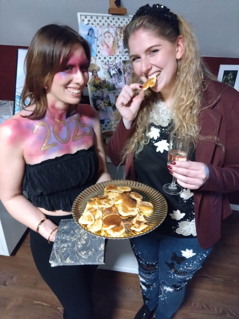 Zwei Mädchen bei der Kalendervorstellung von Stachellyart mit Mini-Pfannkuchen und Sekt zum Anstoßen. Ein Mädchen trägt ein Facepainting mit der Zahl 2025.